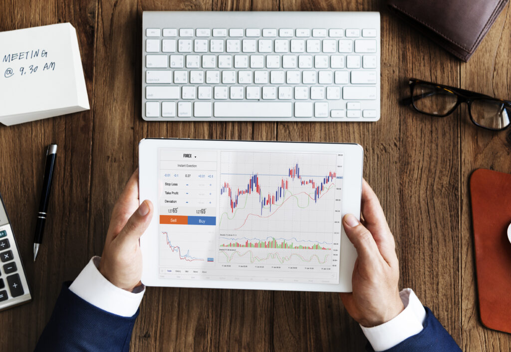 A person in a business suit holding a tablet displaying financial charts and data